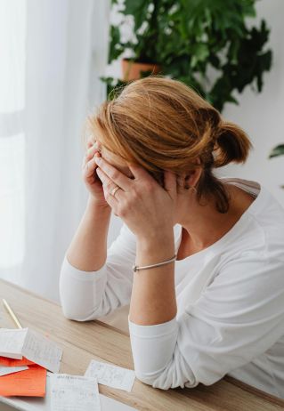 Woman stressed over financial receipts at a desk, dealing with expenses and calculations.